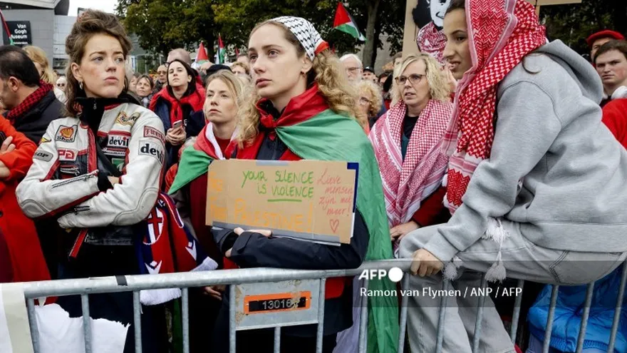 Manifestantes, entre ellos uno que sostenía un cartel que decía "Tu silencio es violencia", participan en una protesta de la "Línea Roja" exigiendo "acciones gubernamentales para detener el genocidio en Gaza" en Ámsterdam el 5 de octubre de 2025.