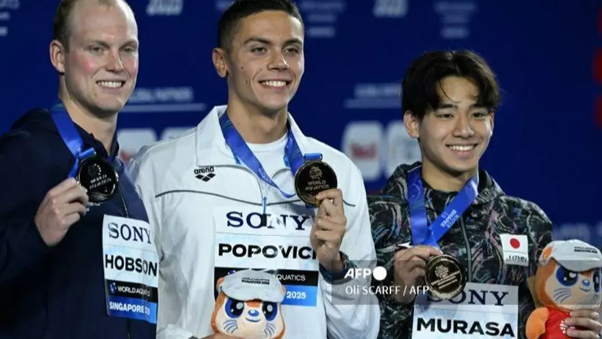 (De izq. a der.) El nadador estadounidense Luke Hobson, medallista de plata, el nadador rumano David Popovici, medallista de oro, y el nadador japonés Tatsuya Murasa, medallista de bronce, celebran en el podio de la prueba de natación estilo libre de 200 m masculina durante el Campeonato Mundial de Acuáticos de 2025 en Singapur el 29 de julio de 2025.