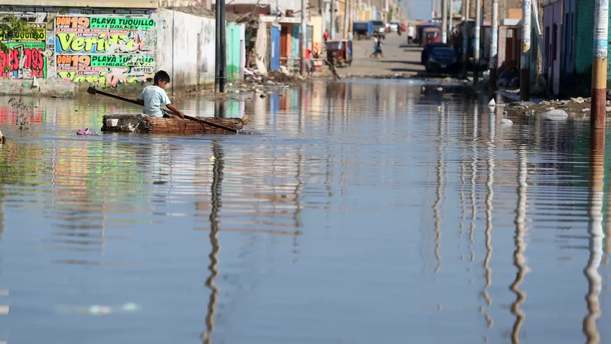 Un niño damnificado del pueblo de Huarmey, se desplaza sobre una pequeña balsa el 22 de marzo del 2017, por una calle inundada de la ciudad de Huarmey en la región costera de Ancash (Per