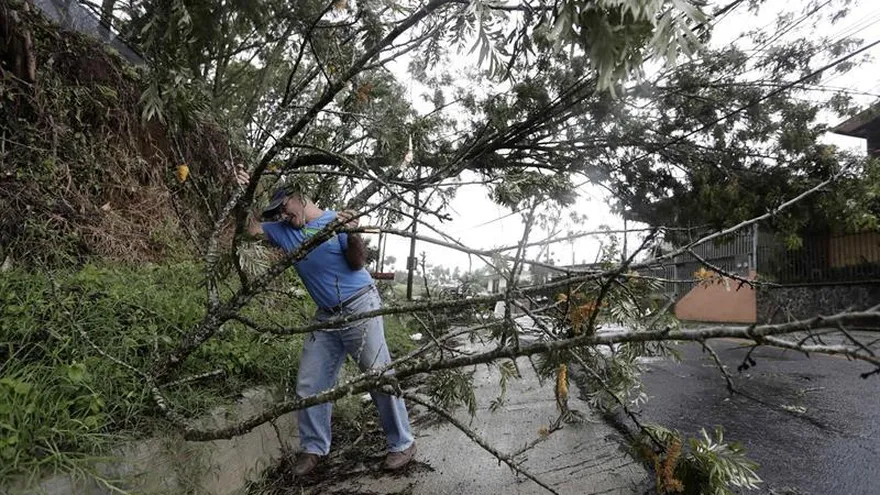 Un hombre trata de limpiar la vía donde varios árboles cayeron al suelo y tumbaron el cableado eléctrico en San José (Costa Rica).