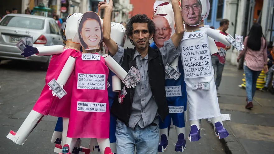Un hombre lleva monigotes que representan figuras políticas como la del presidente peruano Pedro Pablo Kuczynski y el expresidente Alberto Fujimori, que serán quemados en la víspera de Año Nuevo como parte de las celebraciones tradicionales en Perú.