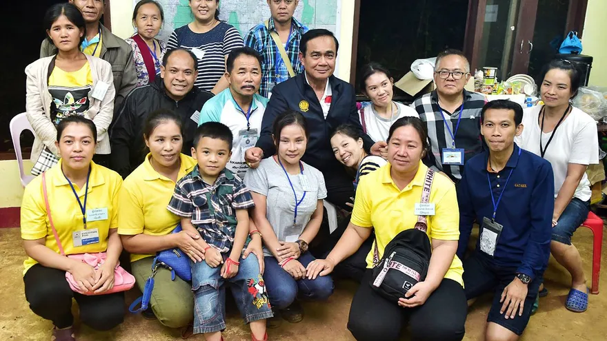 l primer ministro tailandés, Prayut Chan-o-cha (c), posa junto a familiares de los jugadores de fútbol atrapados en una cueva de Tham Luang, en la provincia de Chiang Rai.