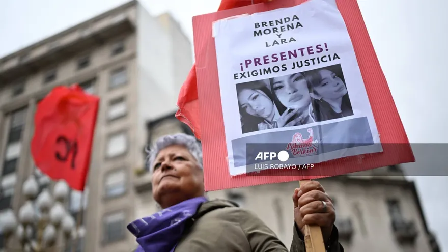 Una anciana sostiene un cartel con las fotografías de Brenda, Morena y Lara, las víctimas del triple femicidio en Argentina.
