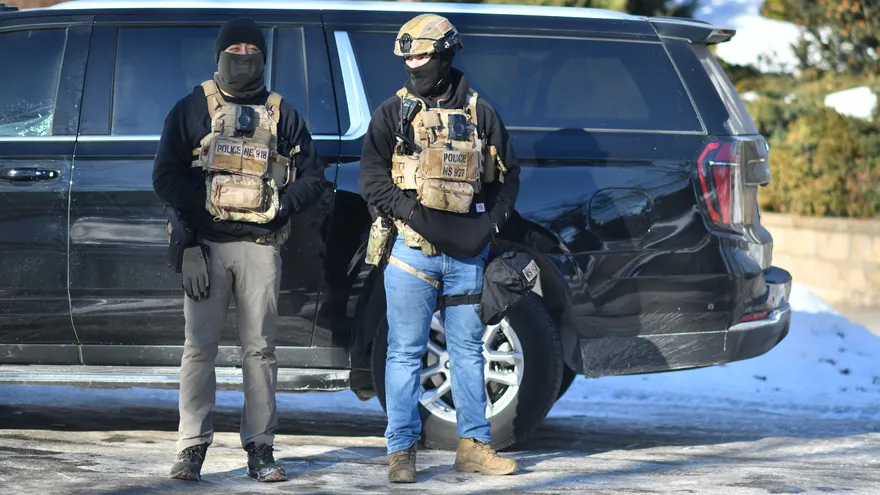 Masked agents stand at an intersection during an ICE immigration enforcement operation in a St. Paul, Minnesota, neighborhood following a multi-vehicle accident on January 31, 2026.