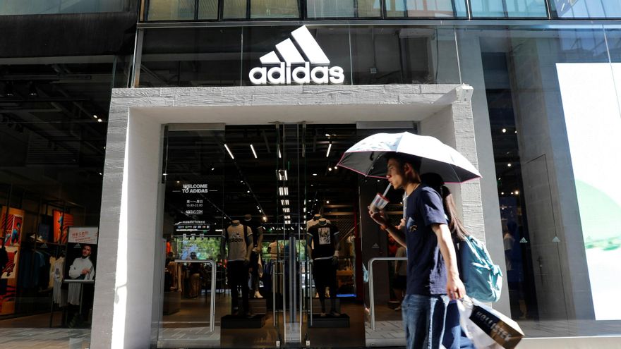 Dos personas pasan por una tienda Adidas, en Pekín, China