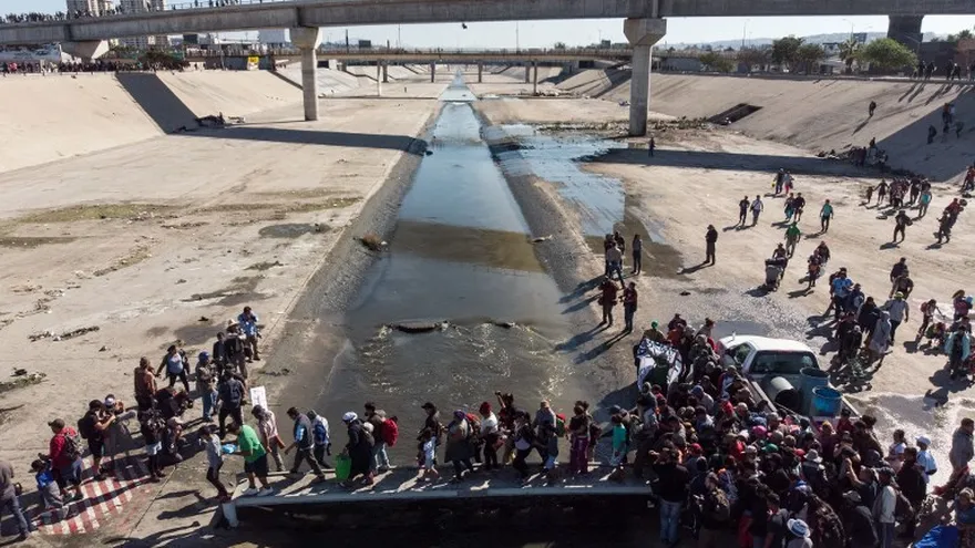 Un grupo de migrantes centroamericanos, principalmente de Honduras, cruza el cauce casi seco del río Tijuana en un intento por llegar al puerto de entrada de El Chaparral, en Tijuana.