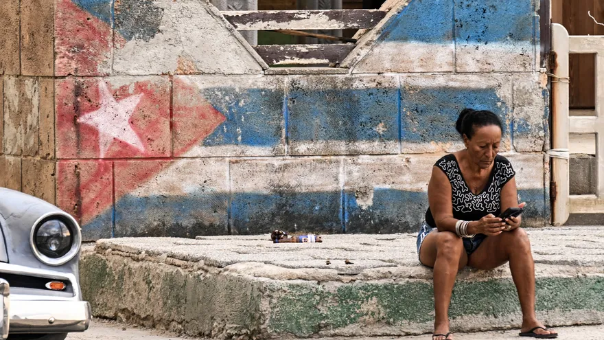Una mujer mira su teléfono celular en una calle de La Habana (2026)