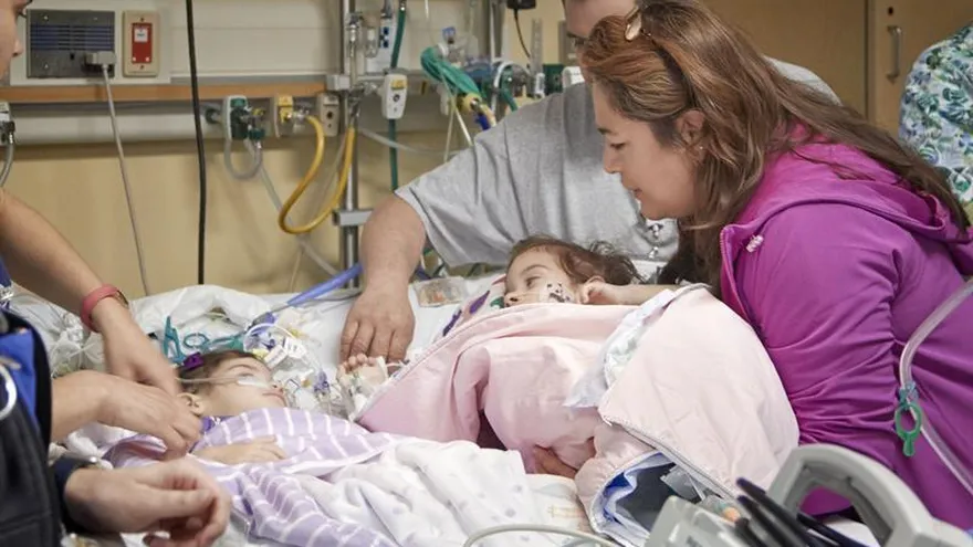 Las hermanas Eva y Erika Sandoval, que hasta hace una semana estaban unidas por su abdomen y compartían órganos vitales, se miran mientras juegan con un camión de plástico rojo en su habitación del hospital.