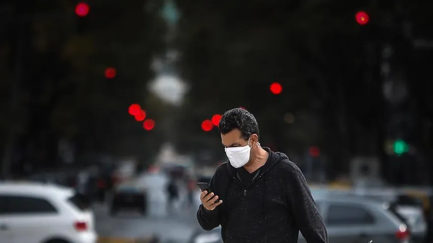 Una persona observa su celular mientras camina en una avenida
