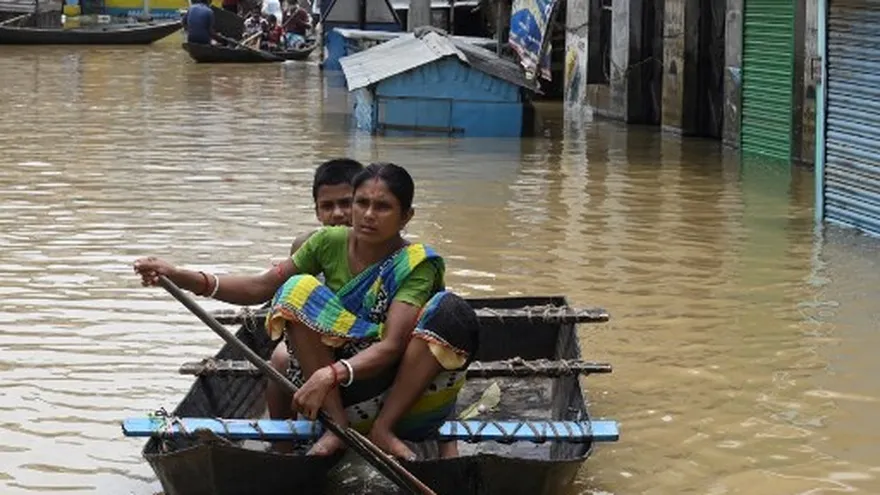 Varias personas a bordo de pequeños botes en las calles inundadas por las lluvias del fuerte monzón