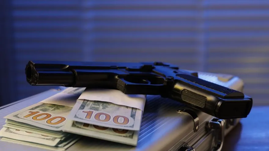 Dinero en efectivo y un arma de fuego. Imagen con fines ilustrativos.