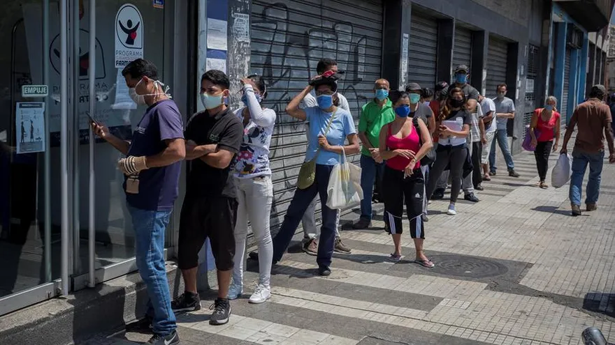 Decenas de personas con tapabocas hacen fila el pasado miércoles para abastecerse de medicamentos y productos de higiene personal en una farmacia de Caracas.