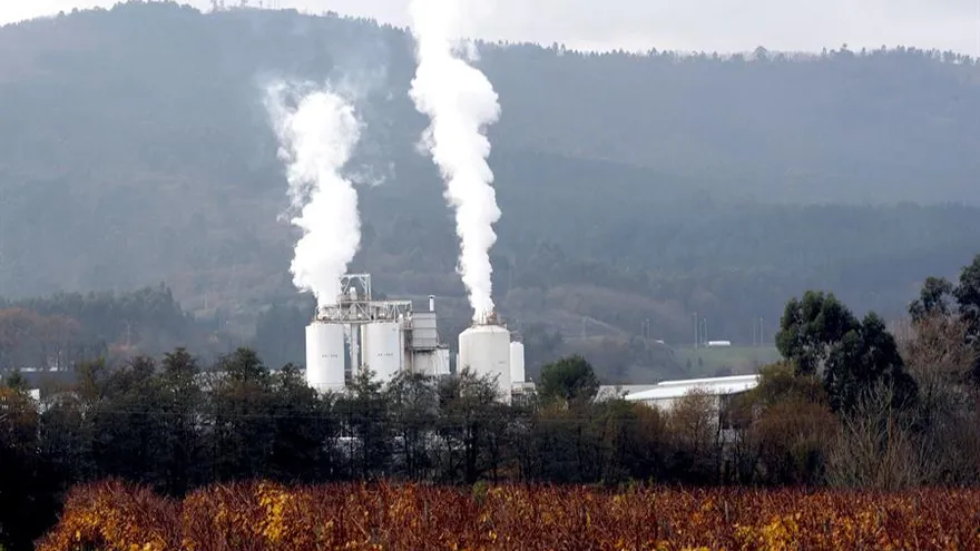 Una empresa realiza emisiones, rodeada de bosques y viñedo