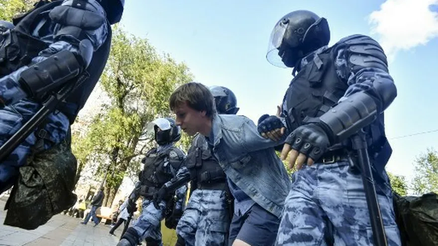 Oficiales de la policía antidisturbios detienen a un hombre durante una manifestación no autorizada que insta a elecciones justas.