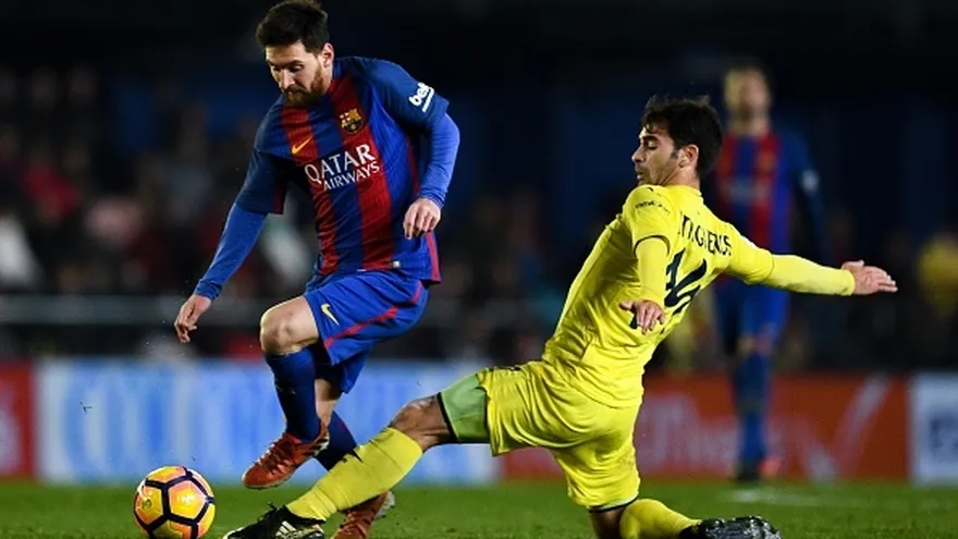 Lionel Messi trata de evadir la marca de Manu Trigueros