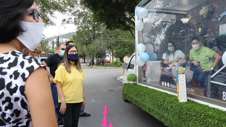 Miembros de la familia Gutiérrez Avila presentan a su bebé ante sus amigos y familiares en una unidad móvil adaptada a la nueva modalidad debido al COVID-19