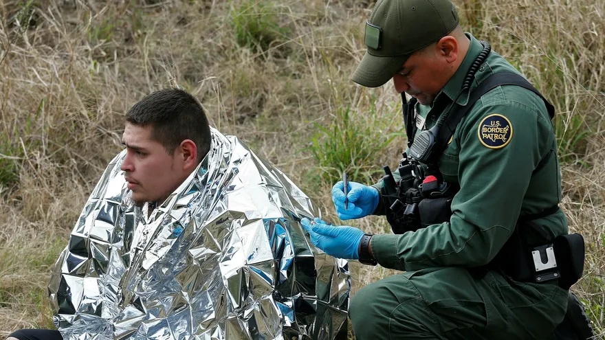 Fotografía tomada el pasado 23 de enero en la que se registró a un agente de la Patrulla Fronteriza de los Estados Unidos al revisar médicamente a un hombre que intentó cruzar el Río Grande para ingresar ilegalmente a los Estados Unidos, en McAllen (Texas, EE.UU.)