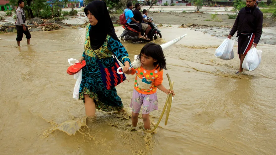 Varios residentes cruzan una calle inundada este lunes en Sentani, en la provincia de Papúa (Indonesia)
