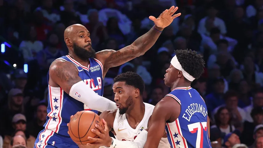 LeBron James (i) y Vj Edgecombe (d) cubren a Donovan Mitchell (c)