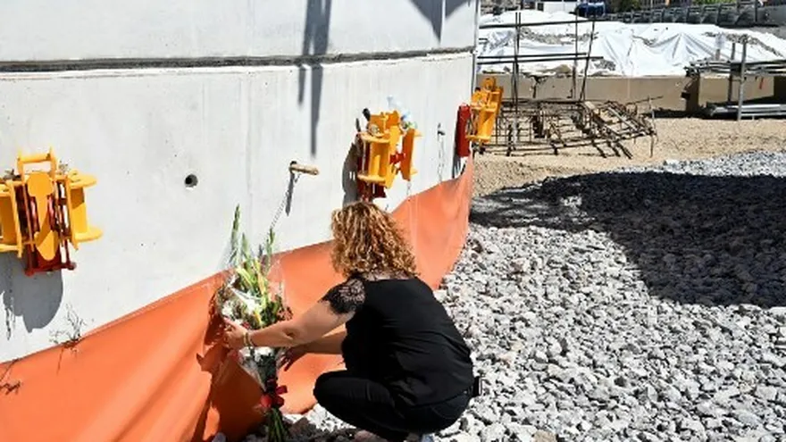 Una mujer deposita un ramo de flores frente al nuevo pilón del puente después de la misa por el primer aniversario de la caída del puente de Morandi, en Génova.