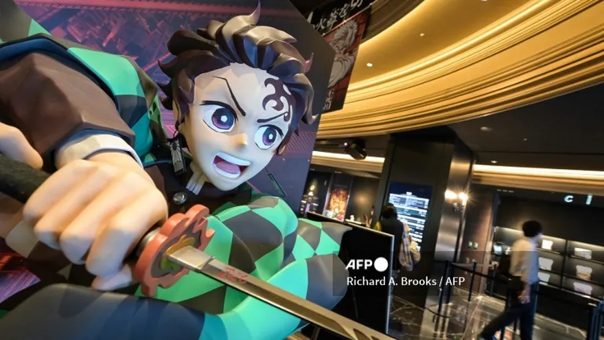 Esta foto, tomada el 9 de septiembre de 2025, muestra a un hombre (derecha) pasando junto a una estatua del joven espadachín Tanjiro Kamado (izquierda), el personaje principal de la película de anime japonesa "Demon Slayer", que se exhibe en un cine en el área de Ikebukuro en Tokio.