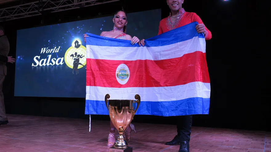 La pareja costarricense David Cruz Vargas y Muriel Nicole Lowis Ortega posan con la bandera de su país tras alzarse con el título de la categoría de "World Salsa Open" del XXI Congreso Mundial de la Salsa.