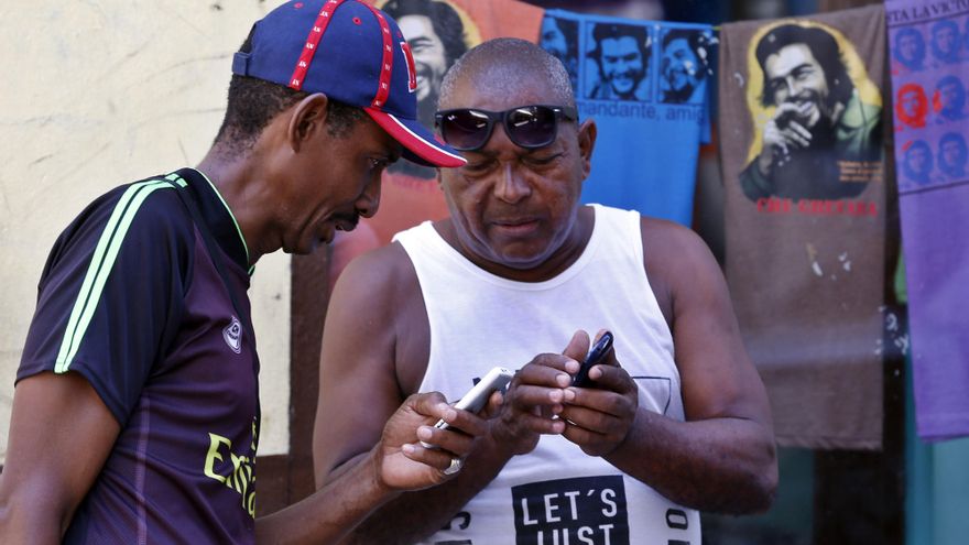 Dos hombres en La Habana, se conectan a internet con sus teléfonos celulares.
