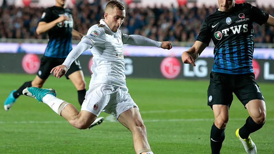 Gerard Deulofeu se dispone a patear el balón mientras Mattia Caldara (d) lo sigue de cerca