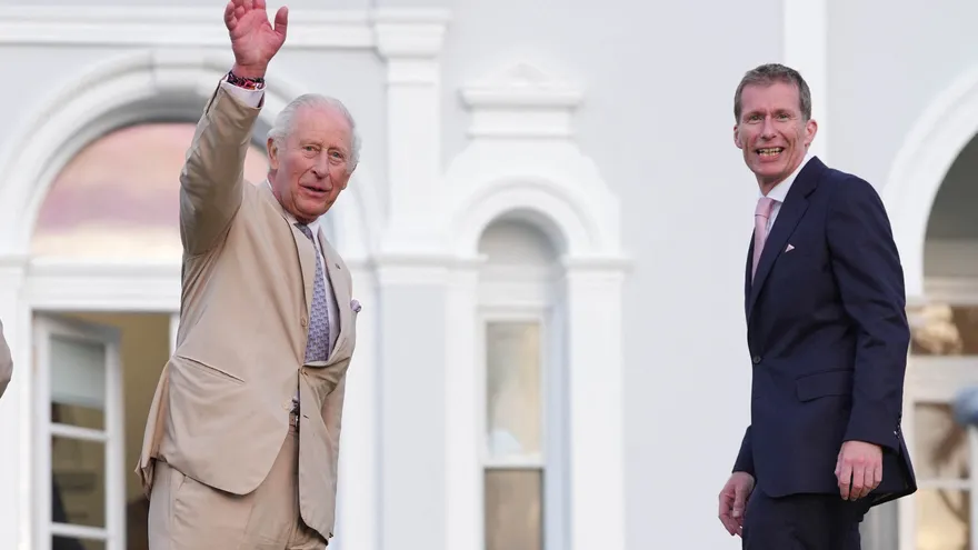 El rey Carlos III de Gran Bretaña se despide con la mano, acompañado por el gobernador de Bermudas, Andrew Murdoch (derecha), al final de una fiesta en los jardines de la Casa de Gobierno en Hamilton, Bermudas.