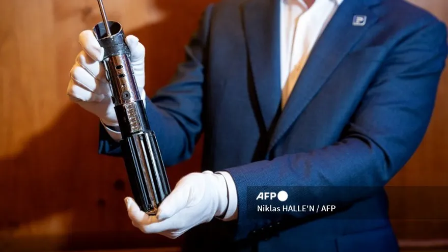 Un miembro del personal sostiene el sable de luz del personaje Darth Vader de las películas Star Wars: El Imperio Contraataca y El Retorno del Jedi durante una vista previa para la prensa de los objetos de la película que se subastarán