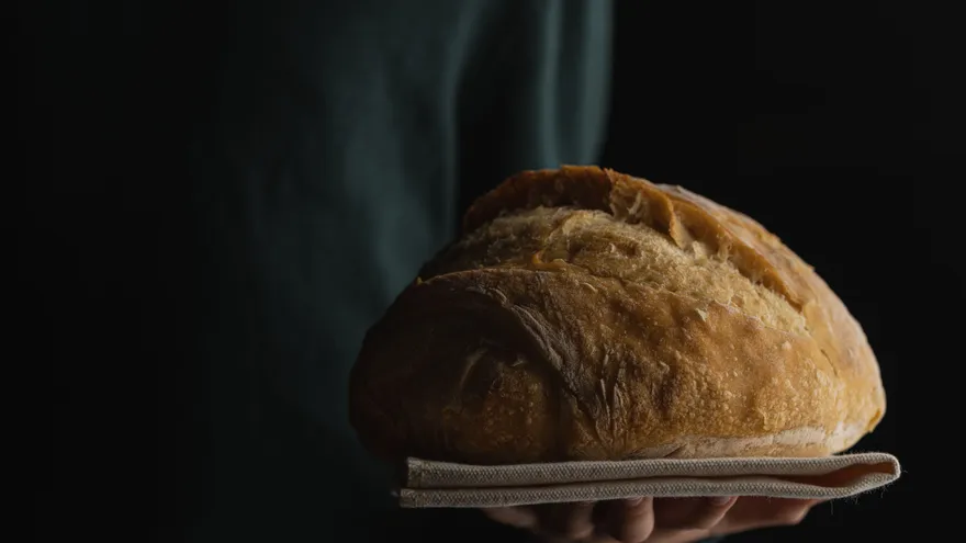 Hombre sostiene un plato con pan. Foto ilustrativa