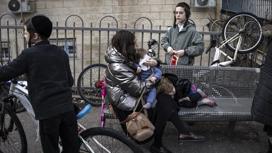 Una mujer sostiene a su bebé en el lugar donde un supuesto sistema de calefacción defectuoso dejó a dos bebés muertos y muchos otros heridos en una guardería en Jerusalén el 19 de enero de 2026.