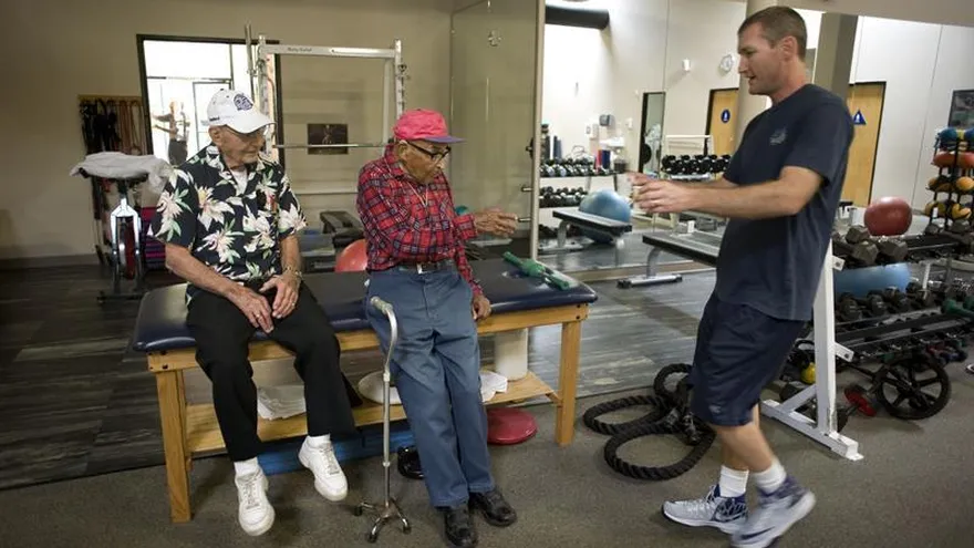 El entrenador Sean Thompson (d) ofrece un vaso de agua a Ray Chavez (c), de 105 años, el sobreviviente más longevo del ataque a Pearl Harbor.