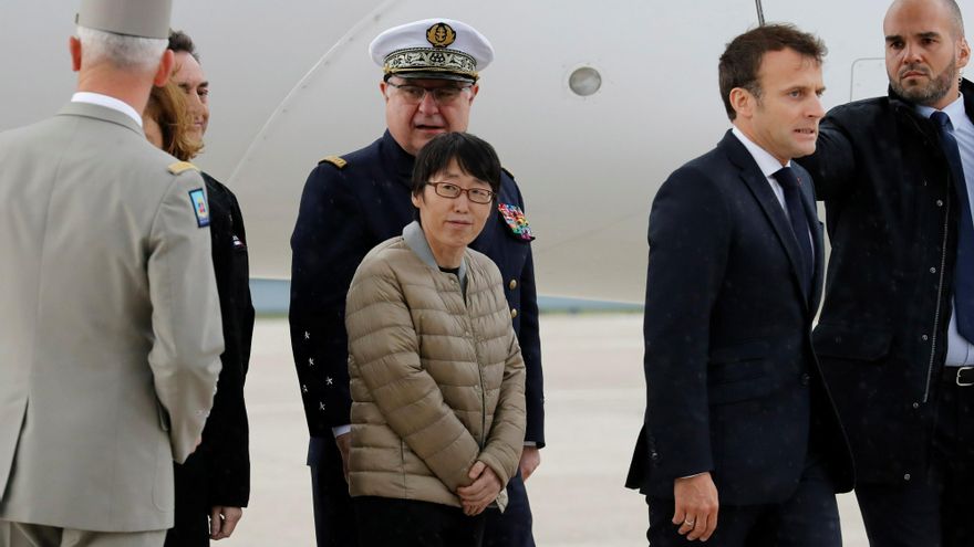El presidente francés, Emmanuel Macron (2d), camina junto a un rehén surcoreano (c), mientras saluda a los rehenes liberados que desembarcan de su avión en el aeropuerto de Villacoublay, cerca de París, Francia