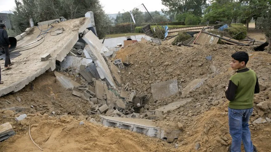 Palestinos se paran sobre los restos de un edificio, que fue destruido después de un ataque aéreo israelí, en Khan Yunis, en el sur de la Franja de Gaza.