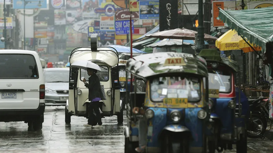 Una mujer tailandesa se protege de la incesante lluvia del martes con un paraguas en la zona turística de Khaosan , Tailandia