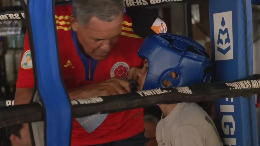 Joven boxeador es asistido por un entrenador