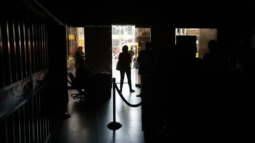 Un grupo de personas permanece en medio de la oscuridad al interior del edificio de la Asamblea Nacional este lunes en Caracas (Venezuela).