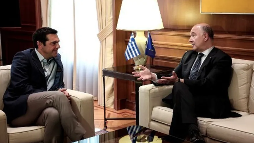 El comisario europeo de Asuntos Económicos y Financieros, Pierre Moscovici, habla con el primer ministro griego, Alexis Tsipras, durante una reunión en la mansión Maximou en Atenas.