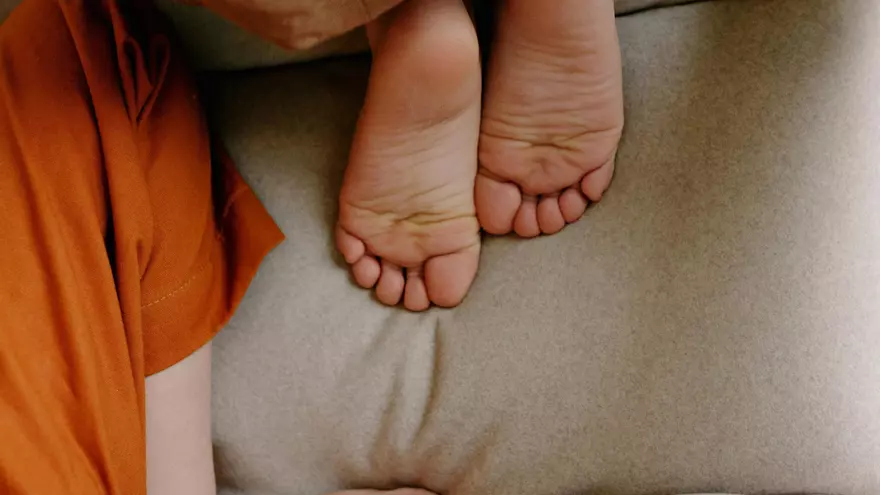 Foto ilustrativa de niños descalzos en un sillón