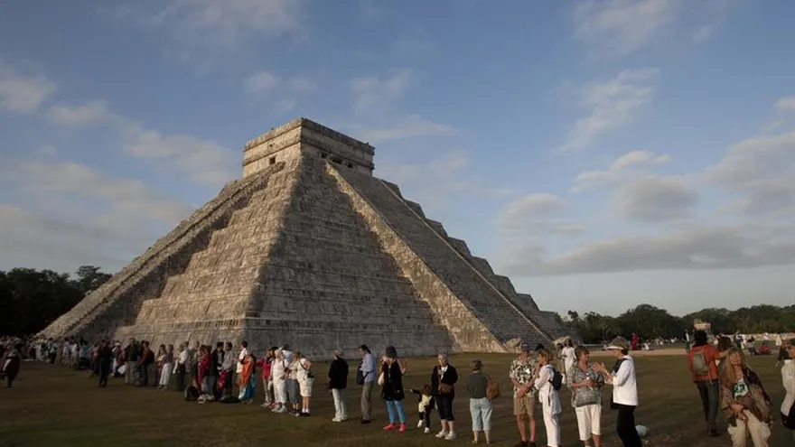 Turistas observan un ritual en las inmediaciones de la pirámide de Kukulkán, de la zona arqueológica de Chichen Itzá, en el estado de Yucatán (México).
