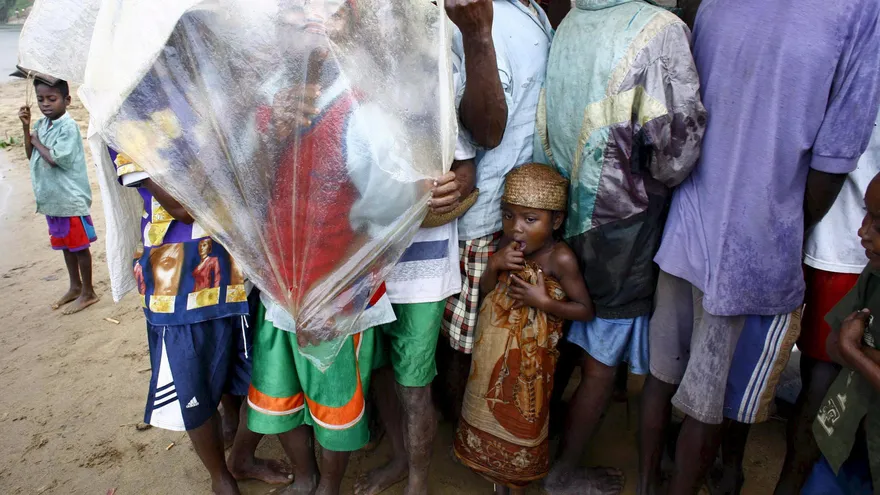 Varios ciudadanos se cubren de la lluvia mientras esperan en la aldea de Nosy Varika, Madagascar