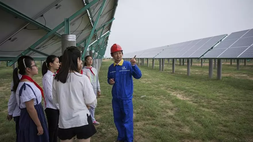 Un trabajador explica el funcionamiento de los paneles solares a un grupo de escolares en la planta de energía solar Panda en Datong (China).