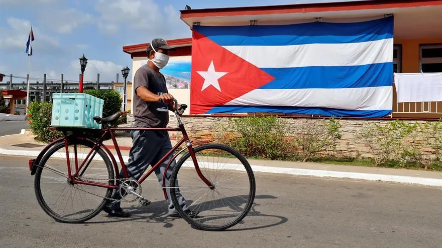 Un hombre pasa frente a una bandera cubana puesta en la fachada de una casa, el martes 28 de abril del 2020.