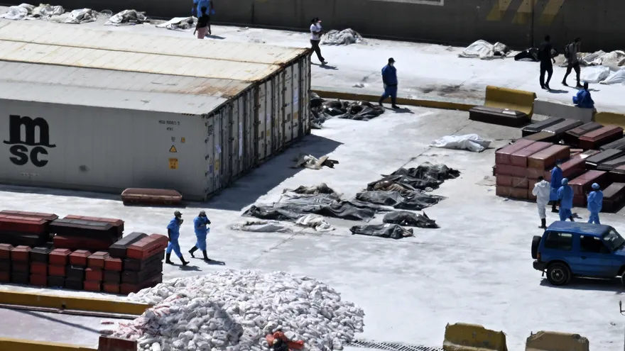 Peritos forenses disponen los cadáveres en el suelo, junto a los ataúdes, en el puerto de La Guaira, Venezuela