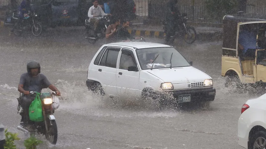 Personas en motos y vehículos circulan bajo la lluvia en Karachi en Pakistán