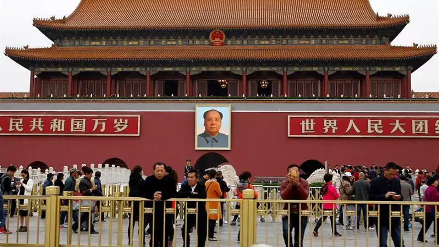 Unos turistas toman fotografías en la Plaza de Tiananmen, bajo un retrato del lidero chino Mao Zedong.