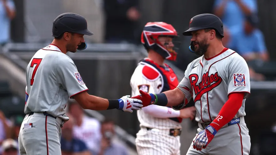 Kyle Schwarber (d) y Trea Turner (i) celebran durante el partido entre Phillies y Mellizos en el Campo de los Sueños