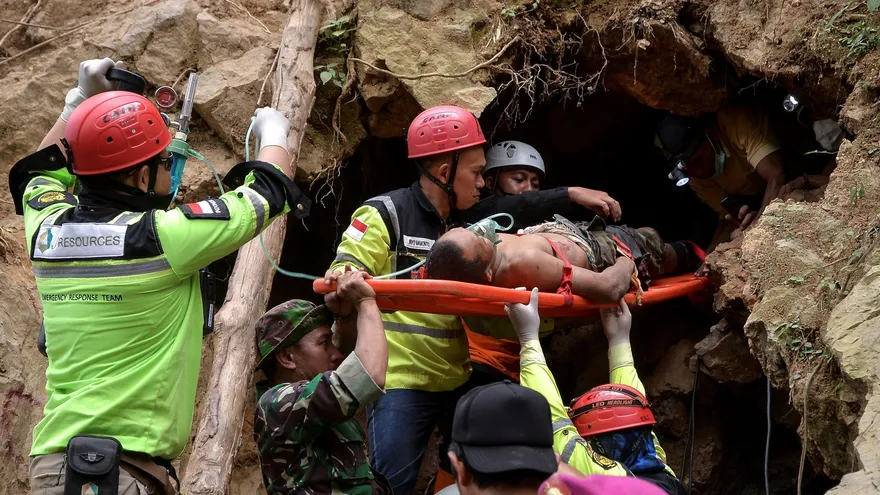 Equipos de rescate indonesios evacúan a un superviviente que quedó atrapado por el hundimiento de una mina de oro ilegal en el municipio de Bolaang Mongondow, este jueves en la isla de Célebes (Indonesia)