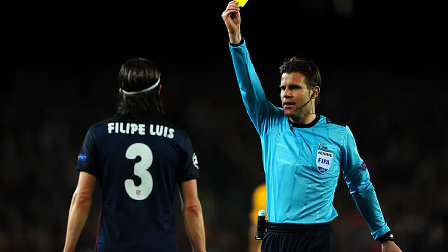Filipe Luis recibe una tarjeta amarilla del árbitro Felix Brych